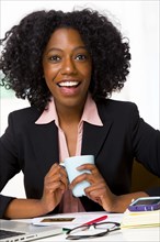 Mixed race businesswoman drinking coffee at desk