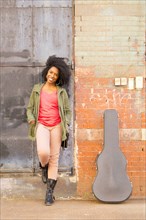 Mixed race woman with guitar case on city sidewalk
