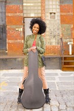 Mixed race woman with guitar case on city street