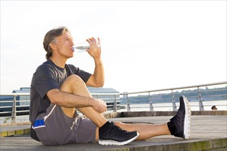 Caucasian runner drinking water in waterfront park