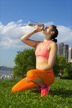 Mixed race woman drinking water in urban park
