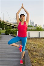 Mixed race woman stretching on boardwalk