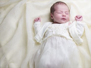 Close up of mixed race newborn baby in christening gown