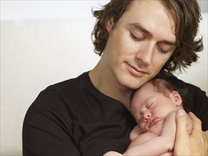 Father cuddling newborn baby