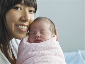 Mixed race mother cuddling newborn baby