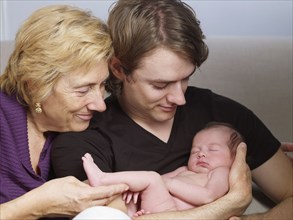 Senior mother and son cuddling newborn baby