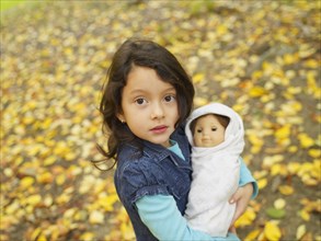 Hispanic girl playing outdoors with baby doll