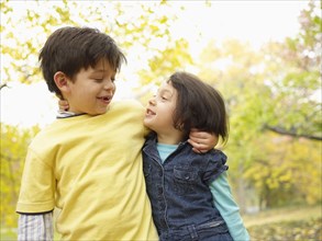Hispanic brother and sister hugging outdoors in autumn