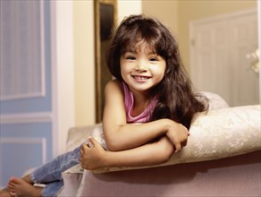 Mixed race girl leaning over edge of sofa