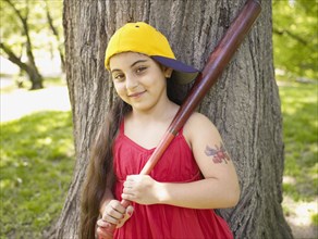 Smiling mixed race girl holding baseball bat