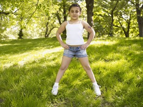 Mixed race girl with hands on hips in grass