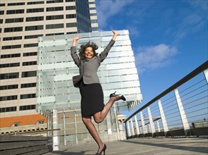 Excited Caucasian Businesswoman standing on one leg in city