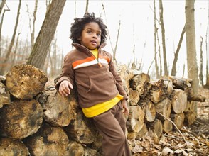 Mixed race boy leaning against firewood