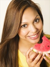 Close up of smiling Hispanic woman eating watermelon