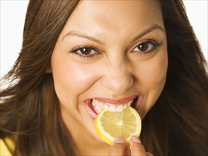 Close up of Hispanic woman biting lemon slice