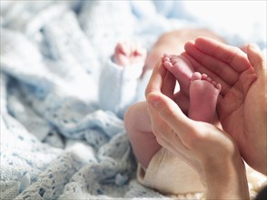Large hands holding tiny newborn's feet