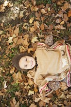 Mixed race girl laying in autumn leaves