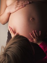 Child patting pregnant mother's stomach