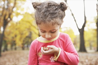 Hispanic girl examining plants outdoors