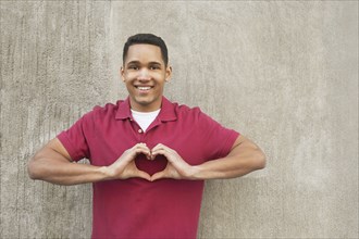 Mixed race man making heart-shape with hands