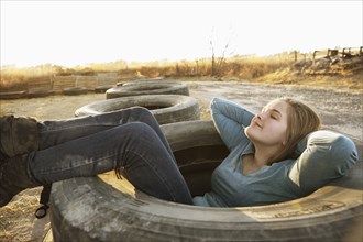 Caucasian teenage girl sitting in empty tire