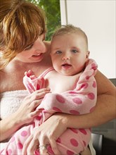 Mother wrapping baby girl in towel