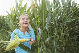Caucasian girl eating corn in field