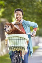 Black woman carrying dog in bicycle basket