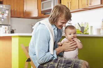 Father holding baby in kitchen