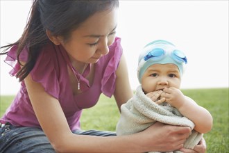 Mother wrapping baby in towel outdoors