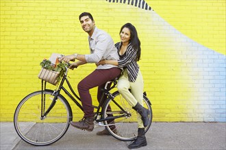 Indian couple riding bicycle on city street