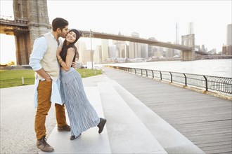 Indian couple kissing by bridge
