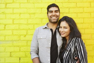 Indian couple hugging in front of yellow brick wall