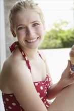Smiling woman in swimsuit eating ice cream cone
