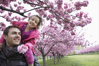 Father carrying daughter on shoulders in park