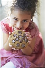 Mixed race girl eating large cookie