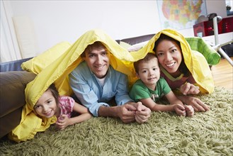 Family playing in blanket fort in living room