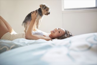 Chinese woman playing with dog on bed