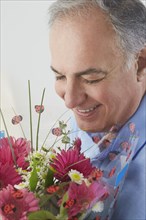 Hispanic man smelling bouquet of flowers
