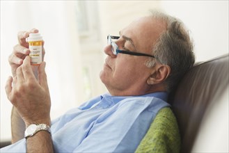 Hispanic man reading prescription medication bottle