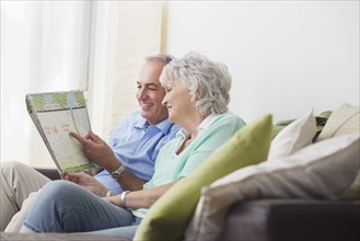 Older couple reading paperwork on sofa
