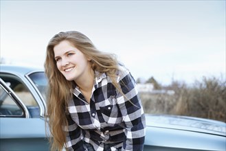 Smiling woman leaning on vintage car