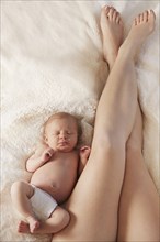Legs of mother laying on bed with newborn baby