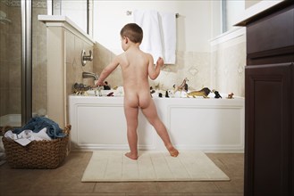 Nude Caucasian boy playing in bathtub