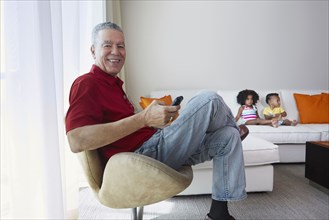 Grandfather relaxing with grandchildren in living room