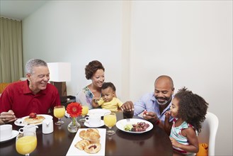 Multi-generation family eating breakfast at table
