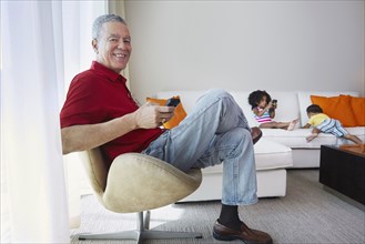 Grandfather and grandchildren relaxing in living room