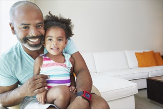 Black father and daughter sitting in living room