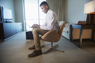 Black businessman using laptop in living room