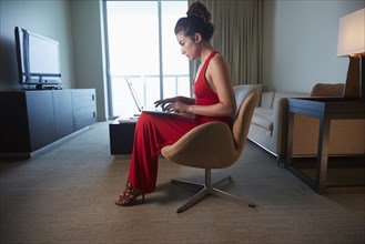 Mixed race woman in evening gown using laptop